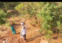 आदिवासी महिला धाडसी डोंगराच्या पायथ्याशी पाण्यात चालत पडण्याचा धोका पत्करतात